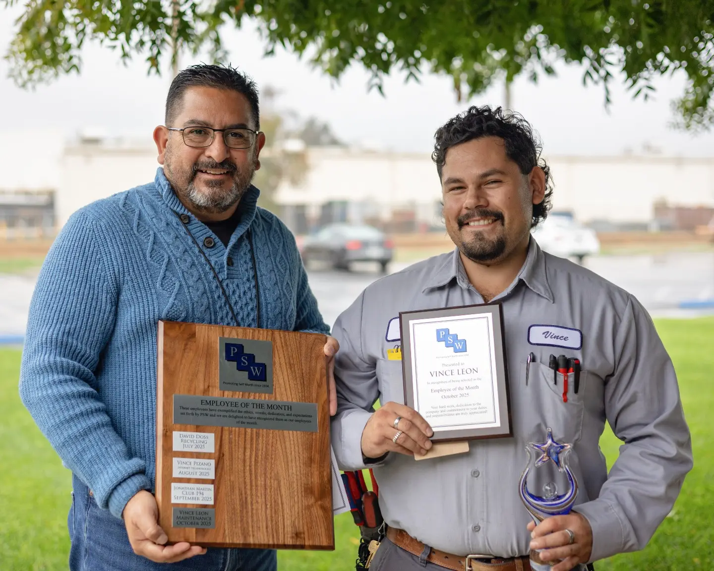 Vince is holding his Employee of the Month plaque while standing next to his director, Rick.
