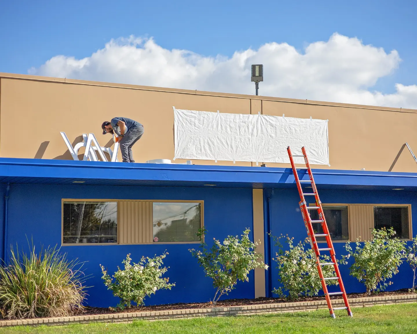 photo of the psw admin building with a man installing new signage